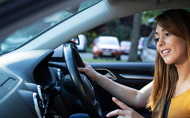 A woman smiling while driving a car.